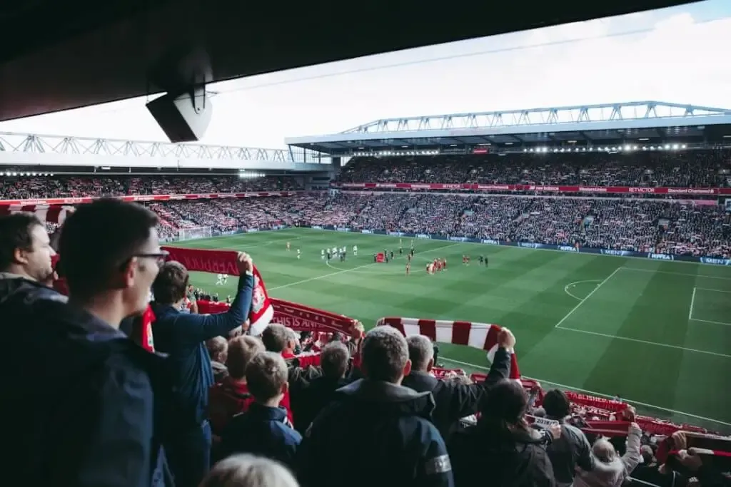Free Fans cheer as players take the field at a vibrant football stadium, creating an electric atmosphere. Stock Photo
