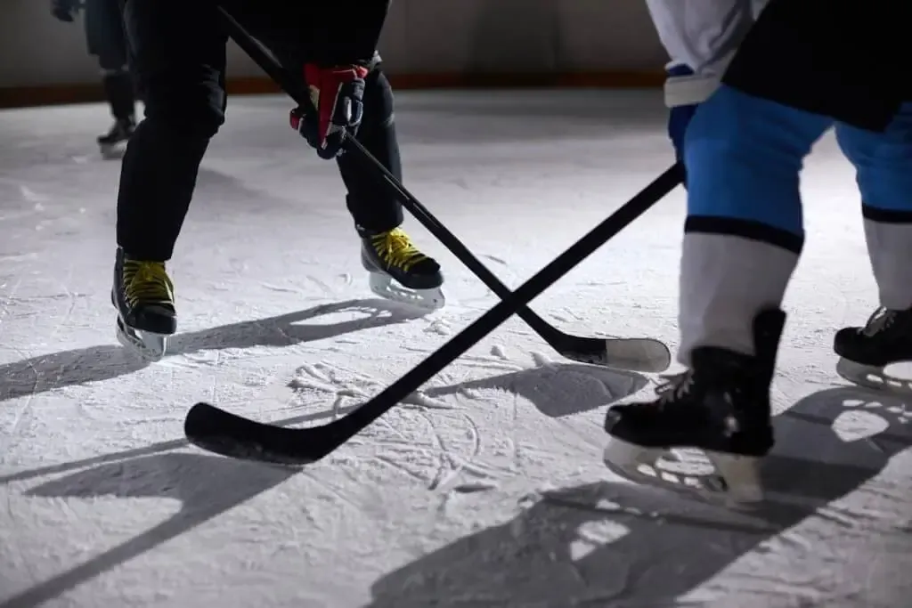 Free Close-up of hockey players battling for puck during an intense face-off on a lighted ice rink. Stock Photo
